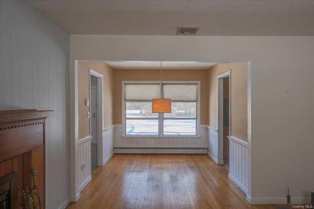 unfurnished dining area with baseboard heating and light hardwood / wood-style flooring