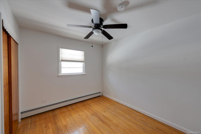 empty room with a baseboard radiator, light hardwood / wood-style floors, and ceiling fan