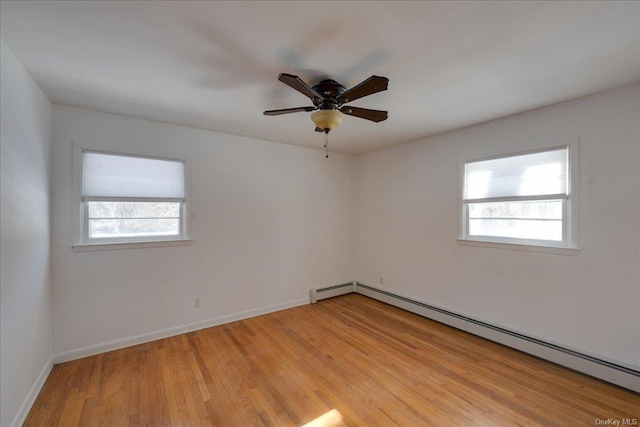 empty room featuring ceiling fan, baseboard heating, and light hardwood / wood-style flooring