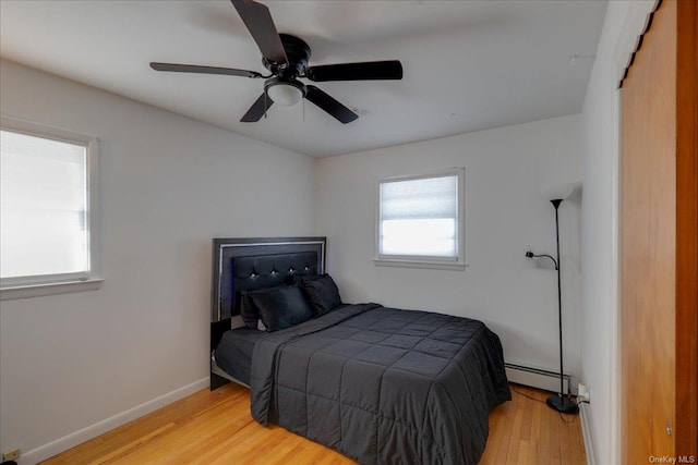 bedroom with light wood-type flooring, ceiling fan, and baseboard heating