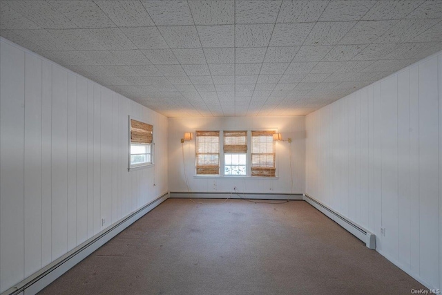 carpeted spare room with a baseboard heating unit