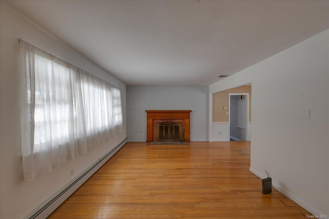 unfurnished living room featuring a fireplace, baseboard heating, and light hardwood / wood-style floors