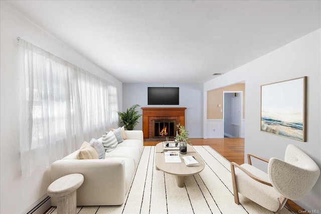 living room featuring light hardwood / wood-style flooring, a fireplace, and baseboard heating