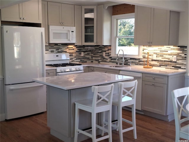 kitchen with white cabinets, a kitchen island, white appliances, and tasteful backsplash