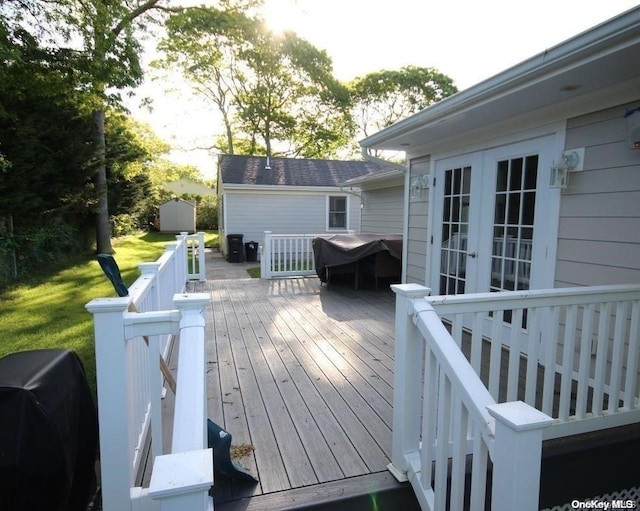 deck featuring french doors, a shed, and grilling area