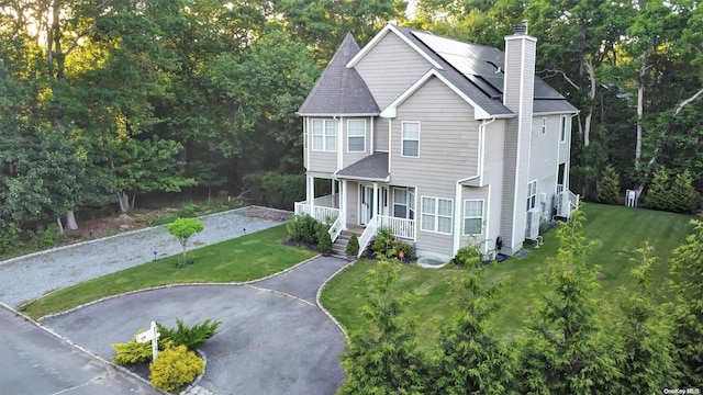 view of front of house featuring a front lawn, covered porch, and solar panels