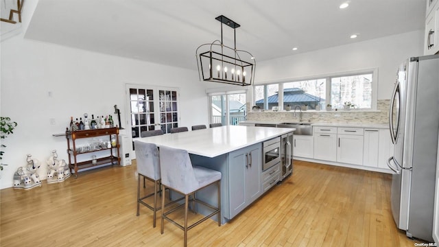 kitchen with white cabinets, a breakfast bar area, a kitchen island, light hardwood / wood-style floors, and stainless steel appliances