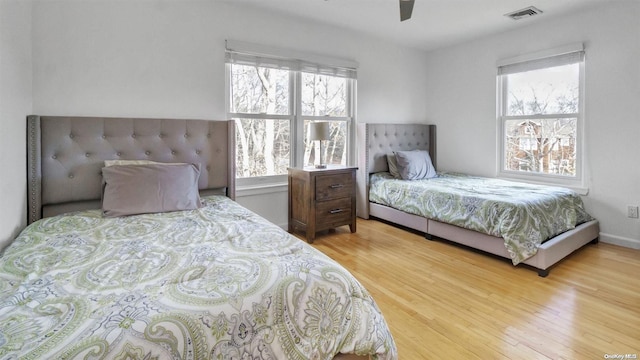 bedroom featuring hardwood / wood-style flooring, multiple windows, and ceiling fan