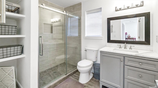 bathroom with wood-type flooring, vanity, toilet, and a shower with door