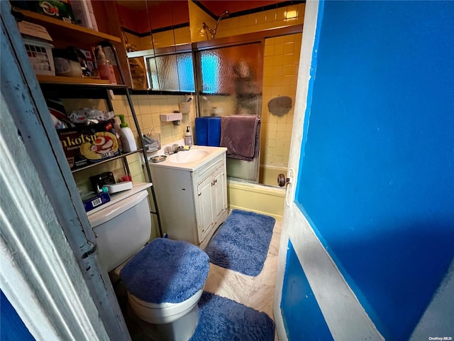 full bathroom with combined bath / shower with glass door, wood-type flooring, toilet, decorative backsplash, and vanity