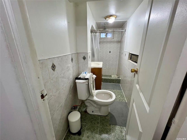 bathroom featuring tile patterned floors, curtained shower, toilet, and tile walls