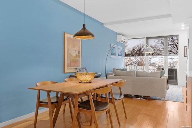 dining space featuring a wall mounted air conditioner and light wood-type flooring