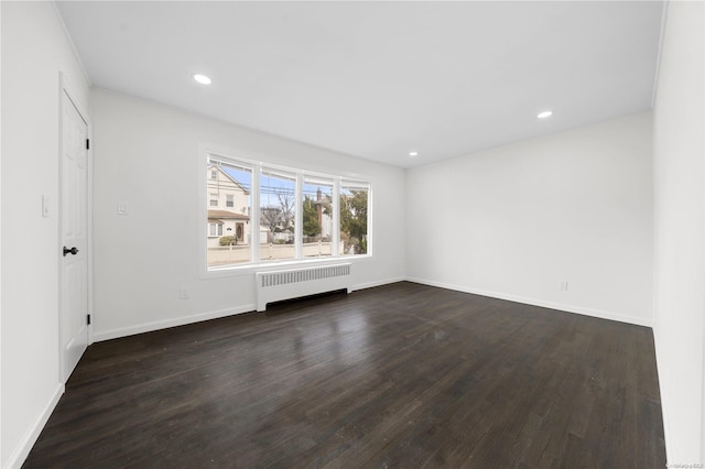 empty room with dark hardwood / wood-style flooring and radiator heating unit