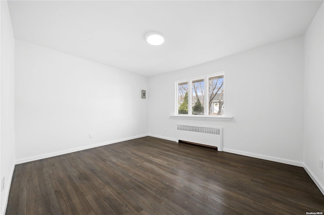 unfurnished room with dark hardwood / wood-style flooring and radiator