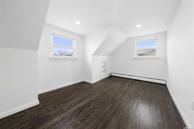 additional living space featuring dark wood-type flooring, a baseboard radiator, and lofted ceiling