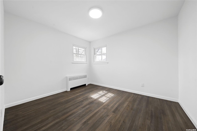 spare room with dark hardwood / wood-style flooring and radiator