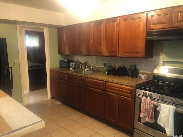 kitchen featuring backsplash, light tile patterned floors, sink, and gas range