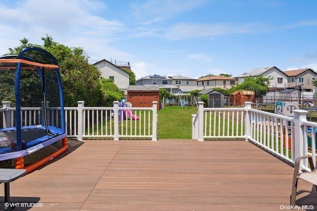 wooden terrace with a yard, a shed, and a trampoline