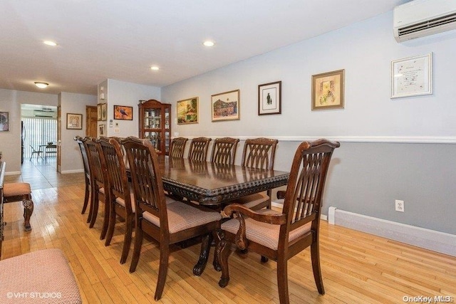 dining room with a wall mounted air conditioner and light hardwood / wood-style floors