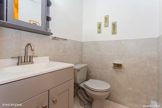 bathroom with tile patterned flooring, vanity, tile walls, and toilet