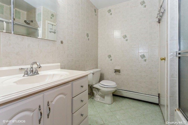 bathroom with tile patterned floors, vanity, baseboard heating, tile walls, and toilet