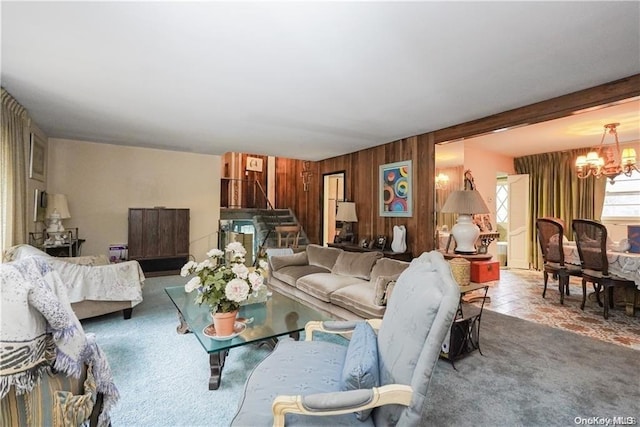 living room featuring wood walls, carpet floors, and a chandelier