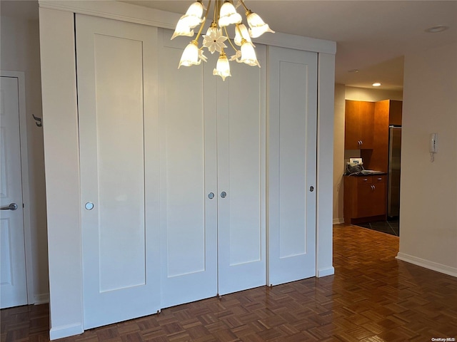 unfurnished bedroom featuring stainless steel refrigerator, dark parquet floors, and a notable chandelier