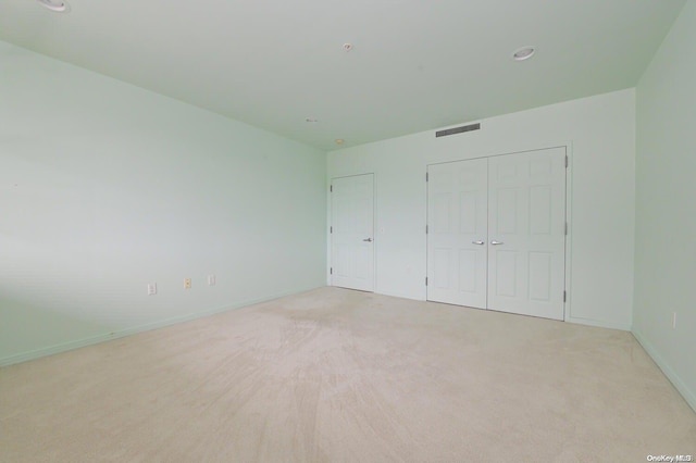 unfurnished bedroom with light colored carpet and a closet