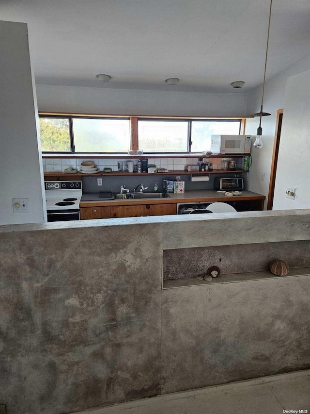 kitchen featuring white range with electric cooktop, concrete flooring, sink, and a wealth of natural light