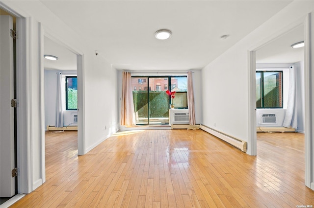 unfurnished room with light wood-type flooring, baseboard heating, and an AC wall unit