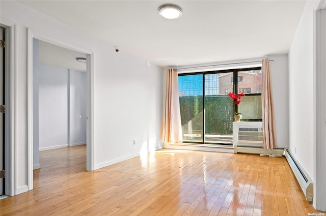 spare room with an AC wall unit, light hardwood / wood-style flooring, and a baseboard heating unit