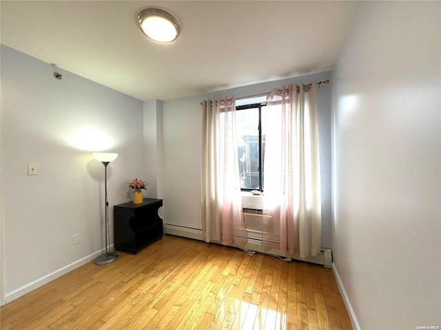 spare room with baseboard heating and light hardwood / wood-style floors