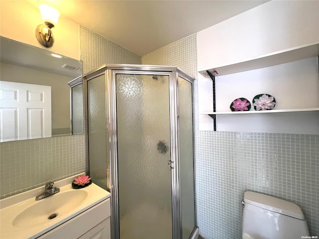 bathroom featuring a shower with door, toilet, and tile walls