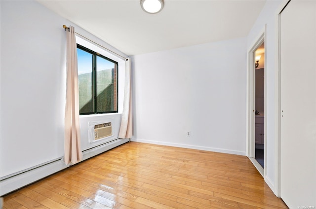 empty room featuring a wall unit AC and light hardwood / wood-style flooring