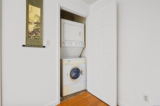 clothes washing area with stacked washing maching and dryer and hardwood / wood-style flooring