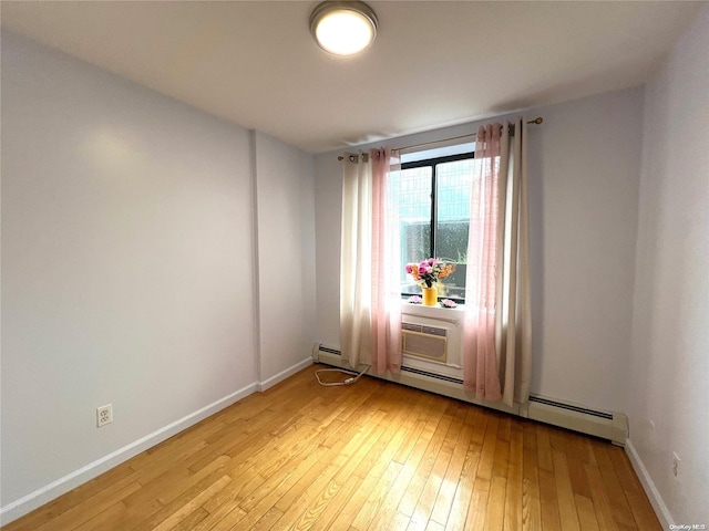 unfurnished room with light hardwood / wood-style floors and a baseboard heating unit