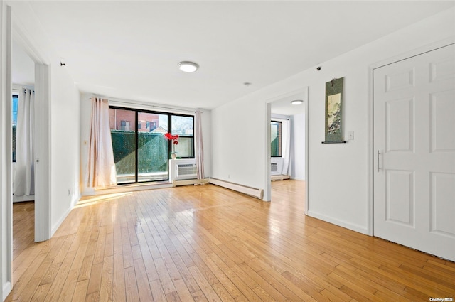 empty room with baseboard heating and light hardwood / wood-style flooring