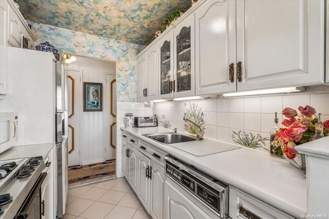 kitchen with dishwasher, sink, light tile patterned flooring, decorative backsplash, and white cabinets