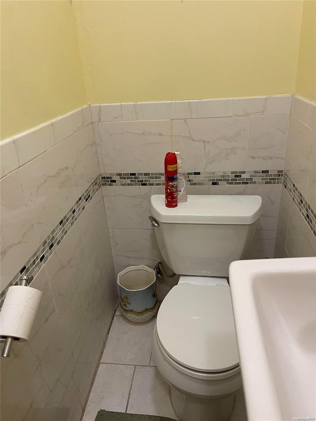 bathroom with sink, tile patterned flooring, tile walls, and toilet