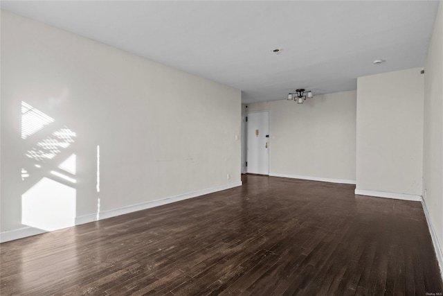 unfurnished room featuring dark hardwood / wood-style flooring and a notable chandelier