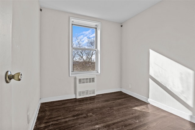 unfurnished room featuring radiator heating unit and dark hardwood / wood-style floors