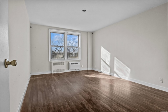 empty room with an AC wall unit, radiator heating unit, and hardwood / wood-style floors