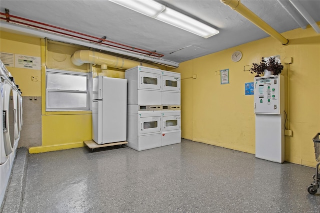 garage featuring washer and dryer, white refrigerator, and stacked washer and dryer