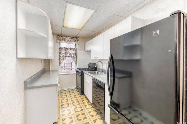 kitchen with a paneled ceiling, sink, black appliances, white cabinetry, and wine cooler