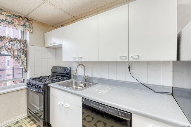 kitchen with sink, a drop ceiling, tasteful backsplash, white cabinets, and black appliances