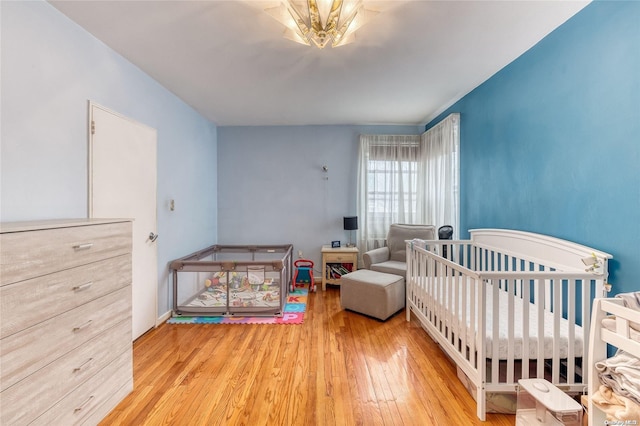 bedroom featuring light hardwood / wood-style flooring and a nursery area