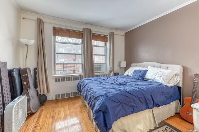 bedroom featuring light wood-type flooring, radiator, and crown molding