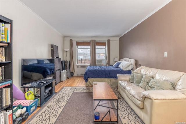 bedroom with radiator, light hardwood / wood-style flooring, and ornamental molding