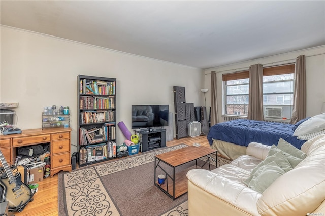 bedroom featuring light hardwood / wood-style flooring, cooling unit, and ornamental molding