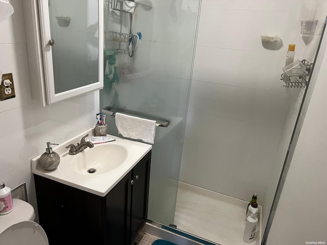 bathroom with vanity, decorative backsplash, toilet, tile walls, and a shower with shower door